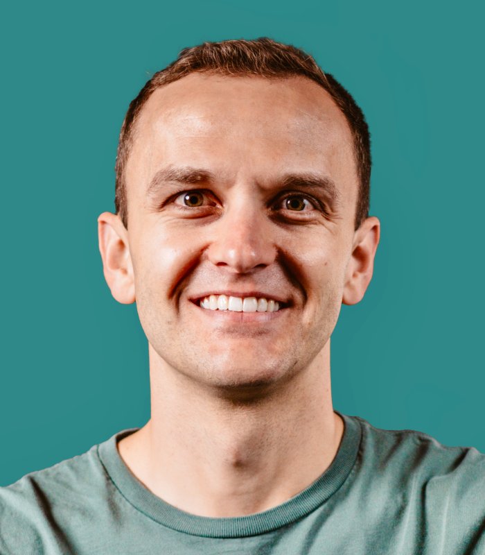 Mark Sommerville, smiling, against his signature teal background